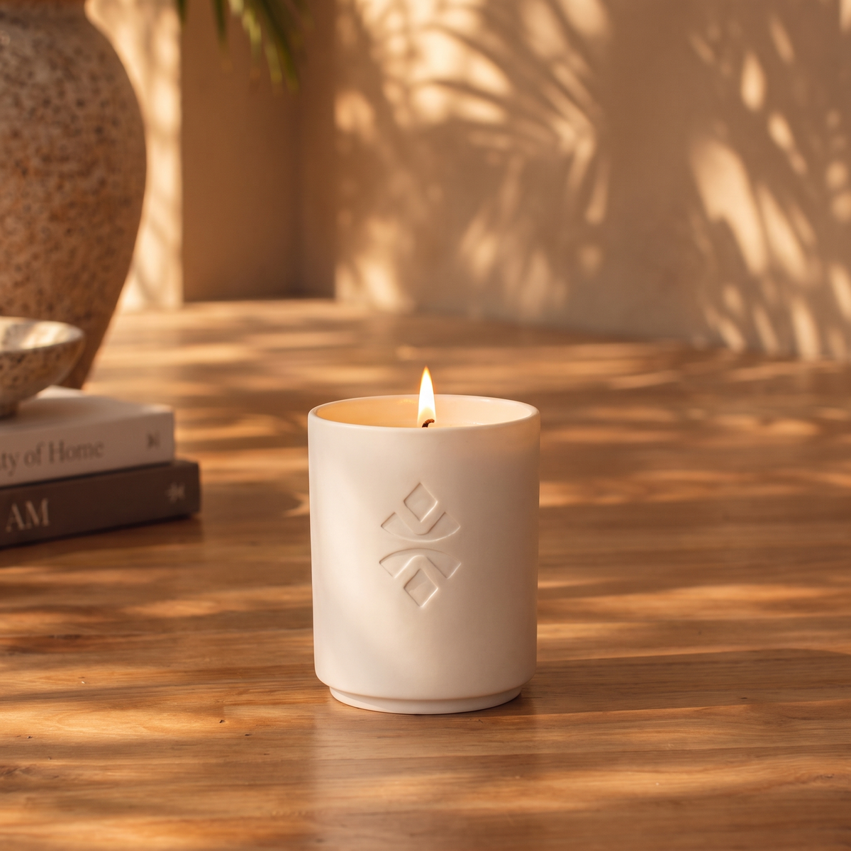 A lit MADOO candle on a walnut table in warm evening light